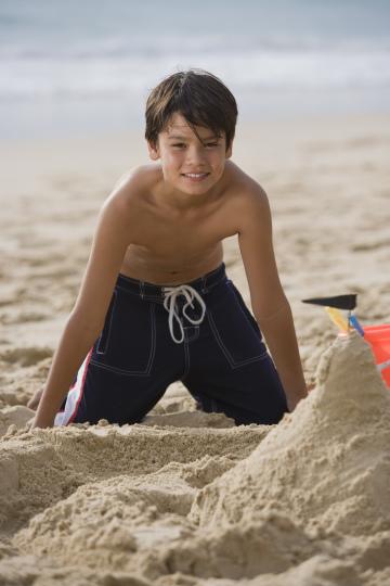 Улыбающийся мальчик строит замок из песка на пляже. Фото Свободно для коммерческого использования, Атрибуция не требуется. Бесплатное стоковое фото для свободного скачивания