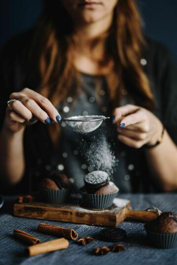 Женщина посыпает кексы сахарной пудрой. Фото Free for commercial use, No attribution required. Бесплатное стоковое фото для свободного скачивания